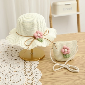Detail of girl's wide brim straw hat and matching bag set with floral accents