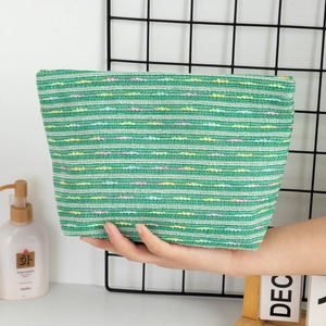 Detail of woven striped makeup bag with colorful accents and secure zipper closure