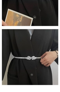 Close-up of a silver elastic leaf buckle belt cinching a black blazer for styling