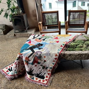 Macro detail of Bohemian woven blanket featuring artistic illustrations and fringe edges