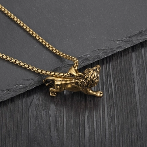 Detail of a golden lion pendant in a running pose on a dark stone and wood background