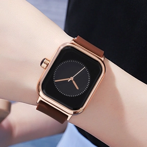 Women's square rose gold watch with black dial and brown silicone strap on wrist