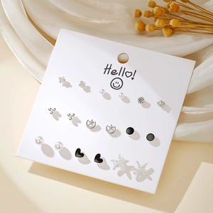 Close-up of 9-pair silver stud earring set with pearls, hearts, and stars on a white card