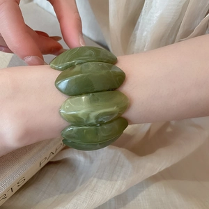 Close-up of a wide dark green marble pattern acrylic elastic bracelet on wrist