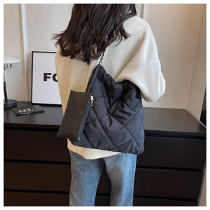 Dettaglio di borsa hobo trapuntata nera con tracolla a catena e pochette con zip abbinata