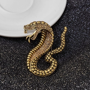 Close-up of vintage gold snake brooch featuring sparkling champagne rhinestones on textured scales