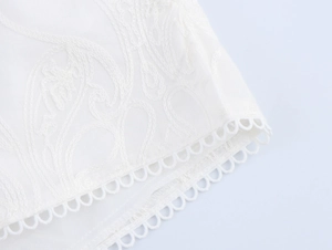 Close-up detail of white lace fabric featuring elegant embroidery and hollow ring lace trim