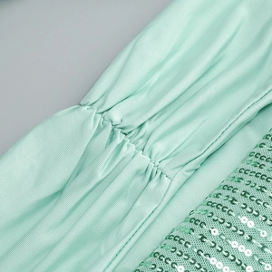 Macro view of mint green rib-knit fabric with sequin embellishments and ruched texture