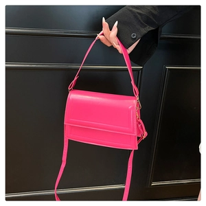 Close-up of vibrant pink shiny leather flap handbag with a matching shoulder strap