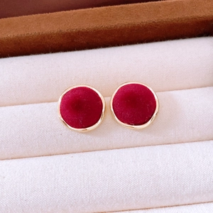 Macro shot of gold-plated round earrings featuring vintage red velvet inlay texture