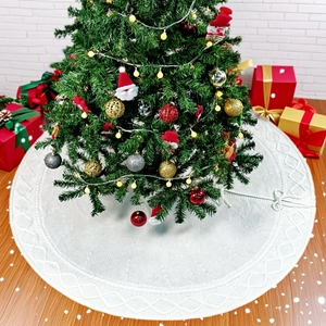 Détail du cache-pied de sapin de Noël en tricot blanc avec motifs tressés et décor festif