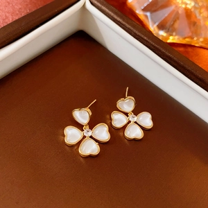 Vue détaillée des boucles d'oreilles trèfle doré avec cœurs en résine blanche et zircon