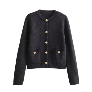 Detail of elegant black knit cardigan featuring vintage golden buttons and twin front pockets