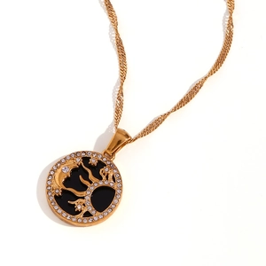 Collana dorata con ciondolo luna e albero e strass bianchi su uno sfondo bianco puro