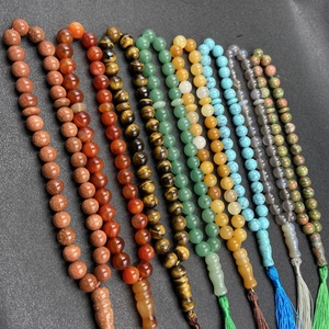 Various natural crystal gemstone prayer beads with silk tassels displayed in neat rows