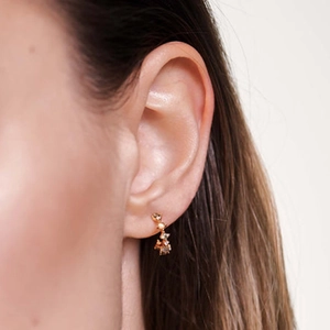 Close-up of gold C-shaped earring with inlaid zircons worn on a model's ear
