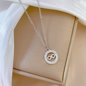 Close-up of silver infinity ring pendant with crystals on silk and leather background