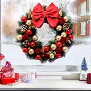 Détail d'une couronne de Noël avec nœud rouge et ornements sur fenêtre enneigée