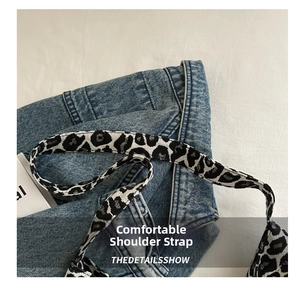 Detail view of denim tote bag featuring a stylish leopard print wide woven shoulder strap