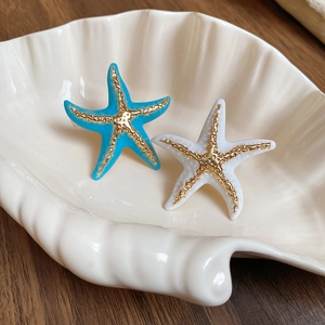 Detailed view of enamel starfish rings in blue and white on a decorative shell tray