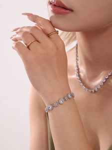 Detail of silver-tone zircon tennis bracelet with clover links on a model's wrist