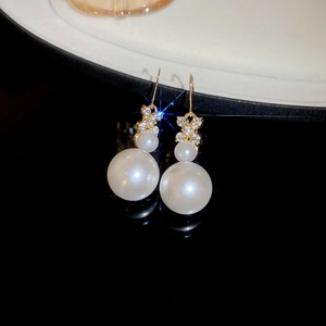 Detailed macro view of gold flower earrings with crystals and hanging white pearls