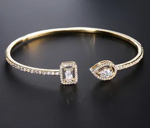 Macro view of gold-plated open bangle with pear and emerald cut zircon stones