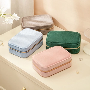 Portable velvet jewelry organizers in multiple colors with gold zippers on desktop