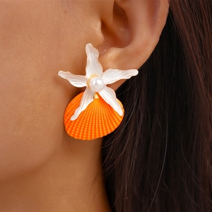 Macro detail of summer star and orange shell earrings with pearl accent on model
