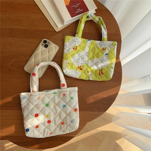 Close-up of quilted cotton mini tote bags with swan and polka dot patterns on wood table