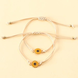 Detail of sunflower woven rope bracelets with yellow enamel pendants on beige cords