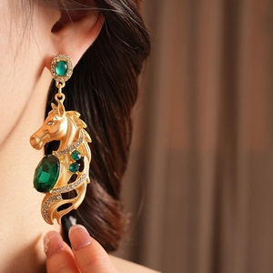 Nahaufnahme von Vintage Pferde-Ohrring in Gold mit grünem Kristall und Strasssteinen