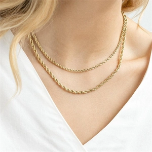 Primo piano di una collana a doppio strato in maglia intrecciata dorata su una modella