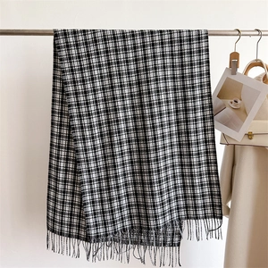 Close-up of black and white plaid scarf with tassels on a hanger with fashion accessories