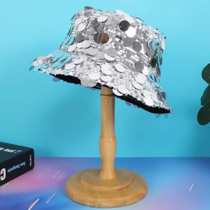 Stylish silver sequin bucket hat for women on wooden stand with blue gradient background