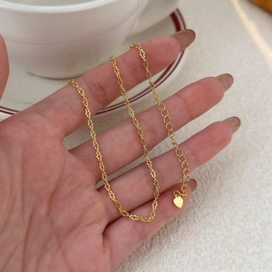 Detail of a minimalist gold petal-link chain necklace with a small heart charm