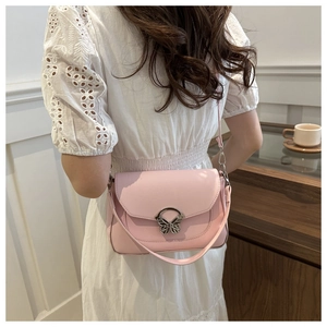 Detail of pink shoulder bag with silver butterfly metal clasp on a white dress