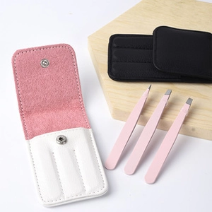 Pink and black leather storage cases with matching stainless steel tweezers on wood