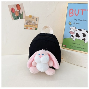 Detail view of a black canvas toddler backpack featuring a cute plush bunny charm