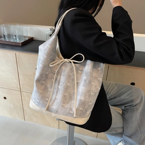 Blue denim tote bag with white bow print shown on model in a modern room setting