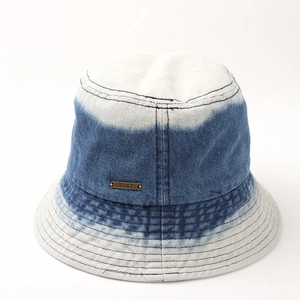 Détail d'un bob en jean avec dégradé bleu et emblème de marque en cuivre vintage