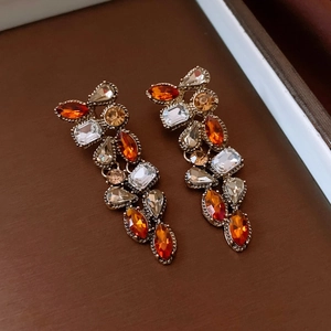 Detail of vintage style drop earrings with orange and champagne rhinestones in metal setting
