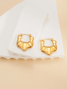 Close-up of golden croissant style hoop earrings on a white geometric display