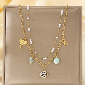 Détail du collier doré double rang avec perles et breloques marines sur fond satin