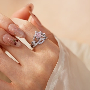 Detailed view of an open star crown ring with a pink heart zircon on a model hand