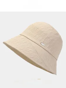 Detailed view of beige sun bucket hat featuring wavy geometric texture and silver logo tag