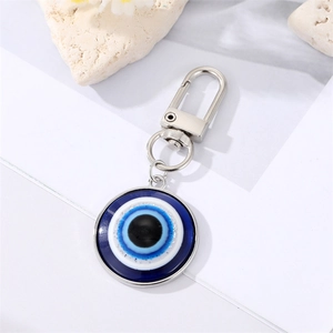 Blue Evil Eye keychain with silver alloy clasp on decorative stone background