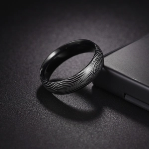 Macro view of Damascus pattern black titanium steel ring with silver wood grain texture