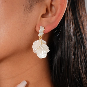 Elegant gold drop earrings with white layered petals and sparkling zircon studs on model