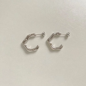 Macro shot of silver wave-shaped C-hoop earrings with small inlaid crystals